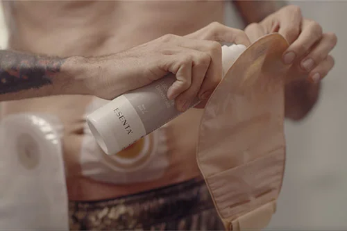 a man applying Esenta spray to an ostomy pouch