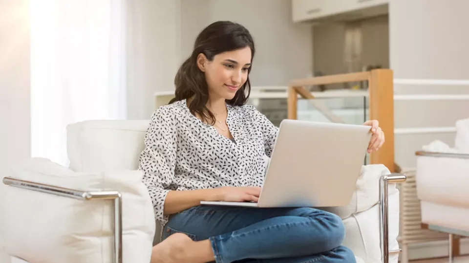 una donna seduta su una sedia che usa un computer portatile